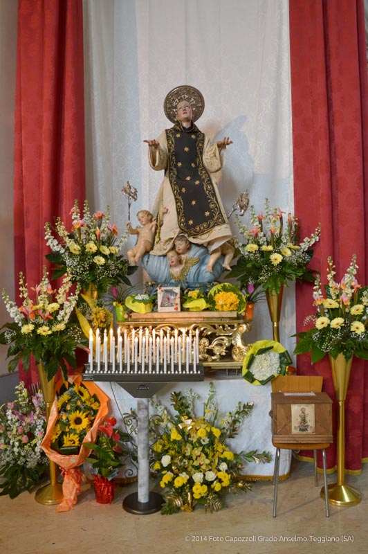 Statua di San Cono circondata da fiori